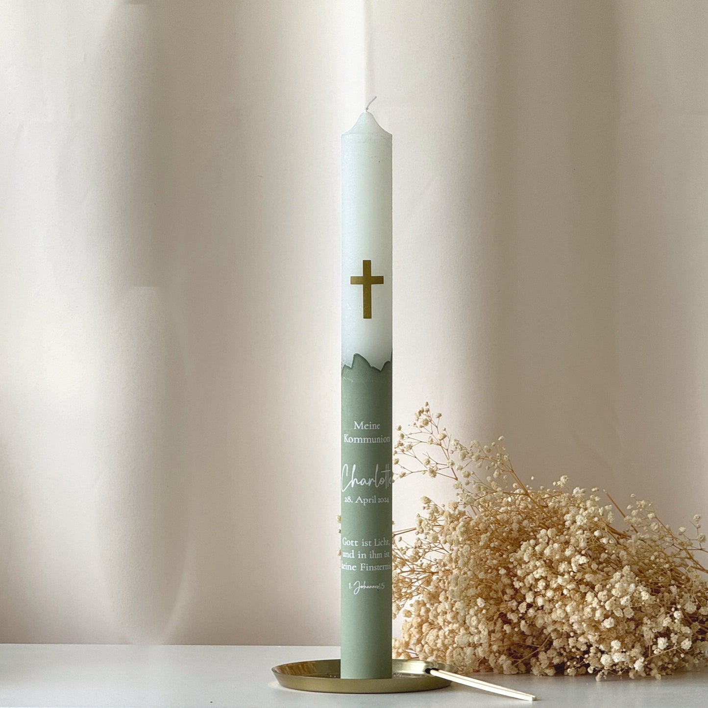 Frontansicht einer Taufkerze oder Kommunionskerze mit grünem Sockel und goldenem Kreuz als Motiv