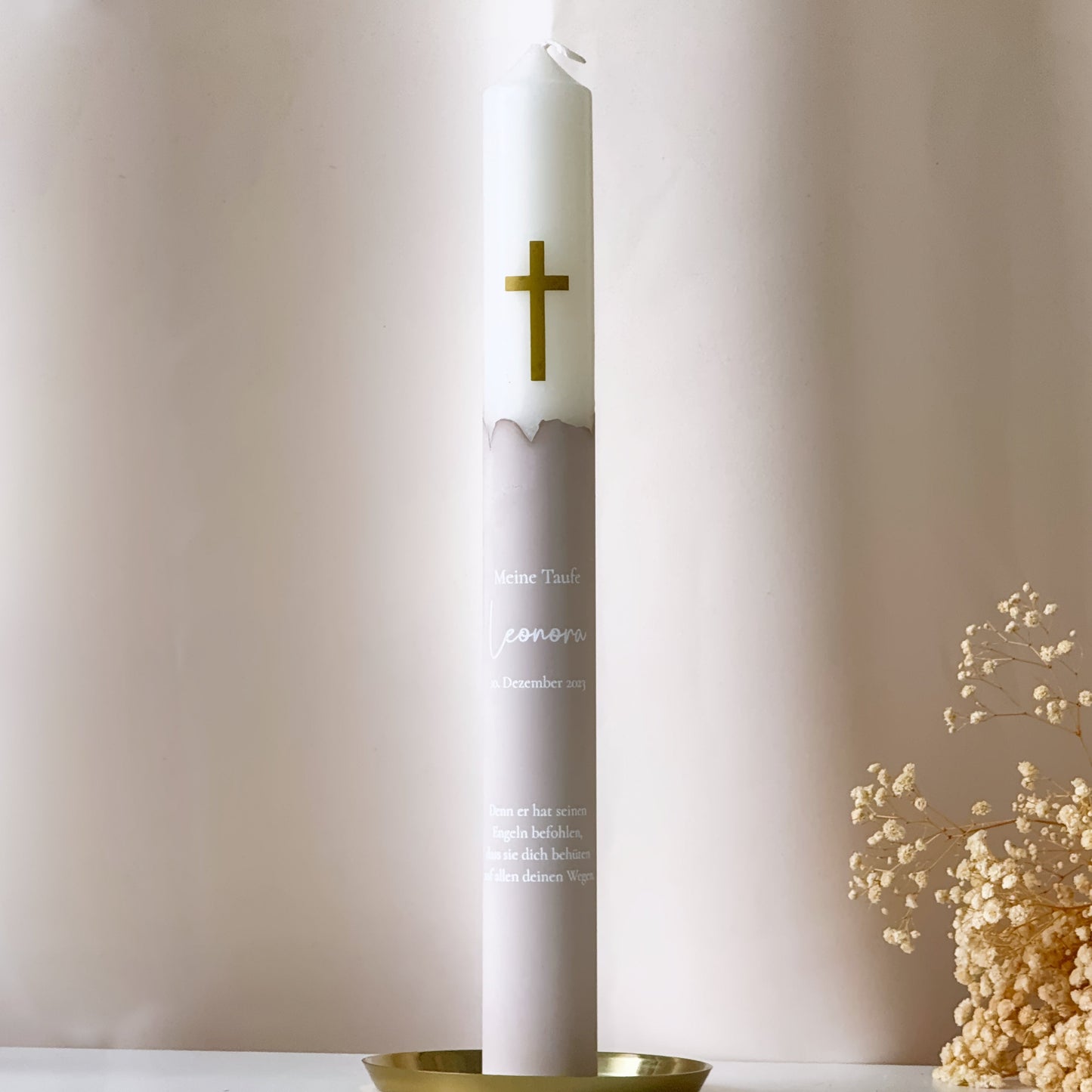 Frontansicht einer Taufkerze oder Kommunionskerze in beige mit goldenem Kreuz als Motiv